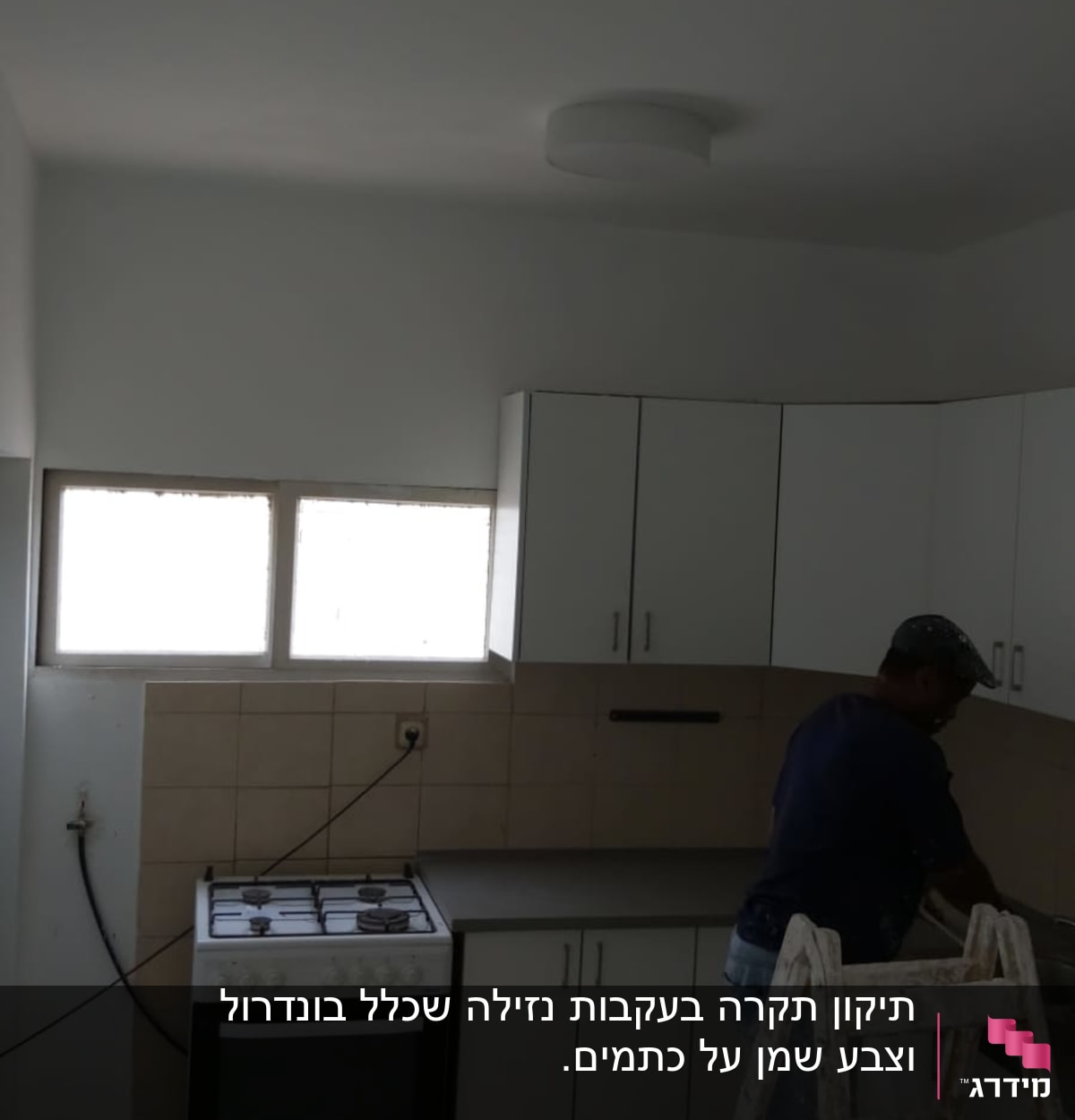אדם צובע קיר במטבח עם סולם